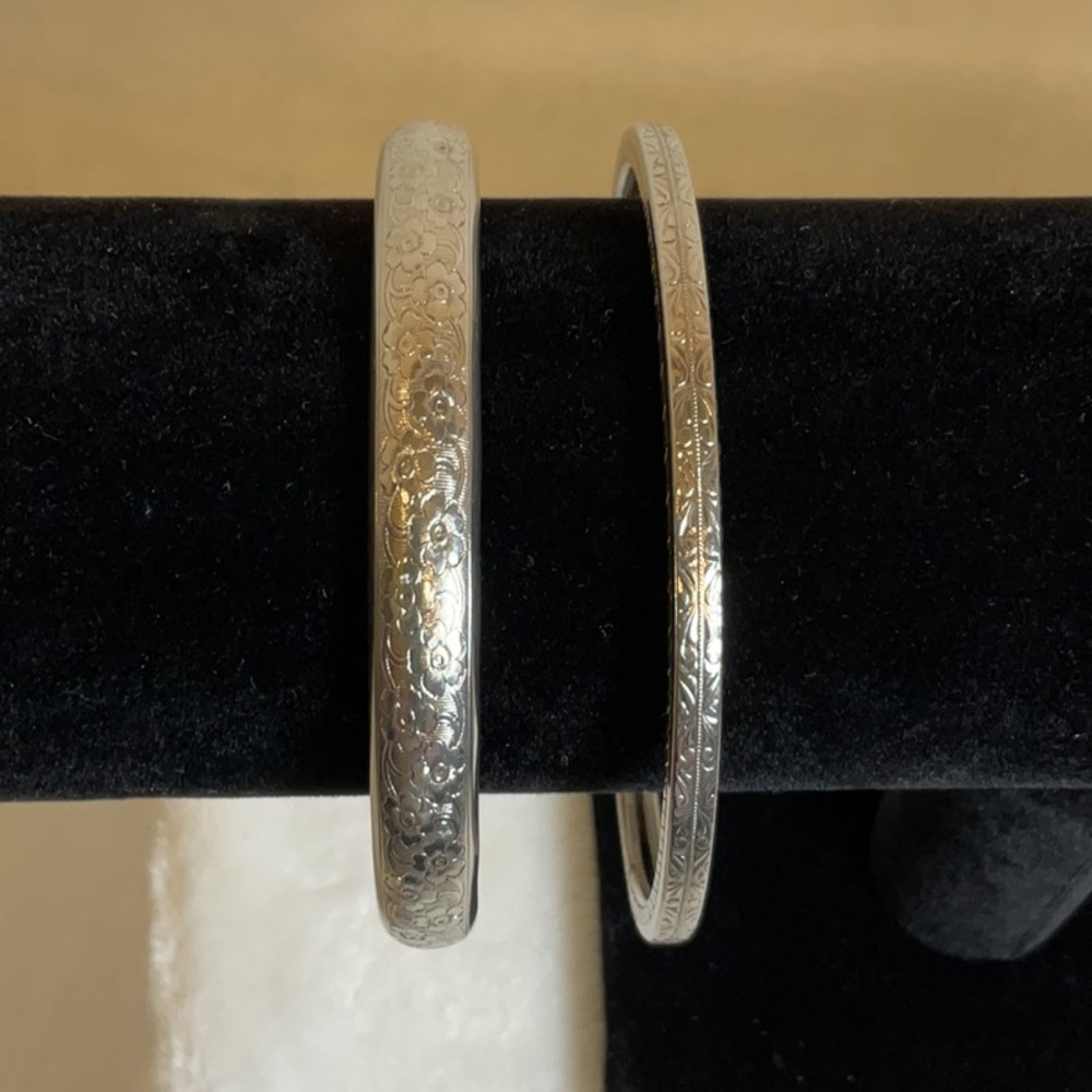 Metal bangle bracelets. Set of two. Each with ornate detailed design.